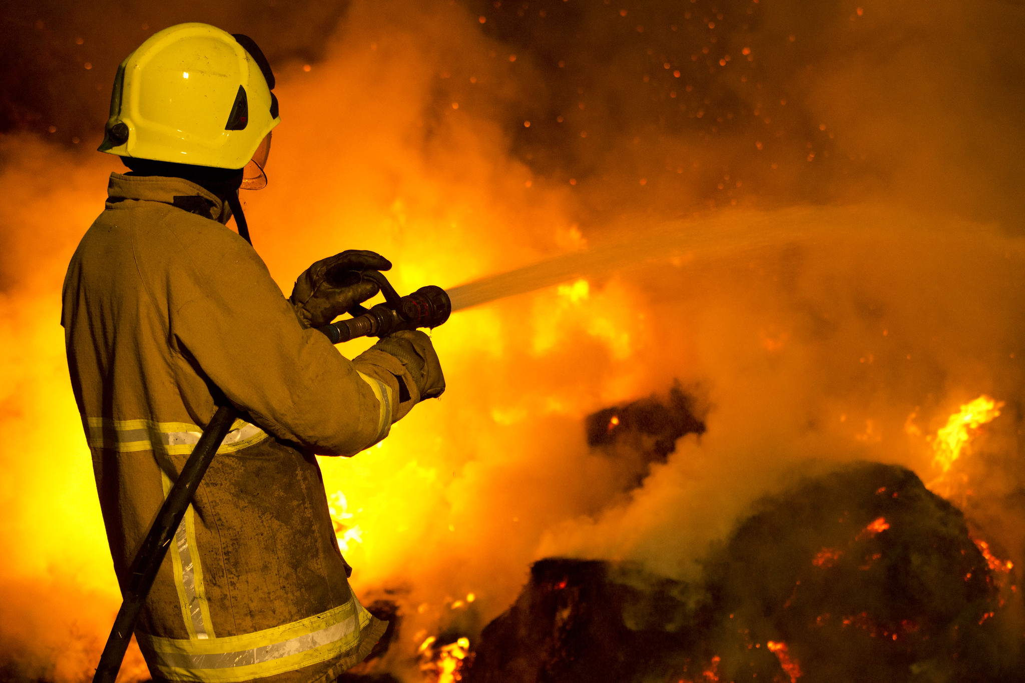 Firefighter pointing hose at fire