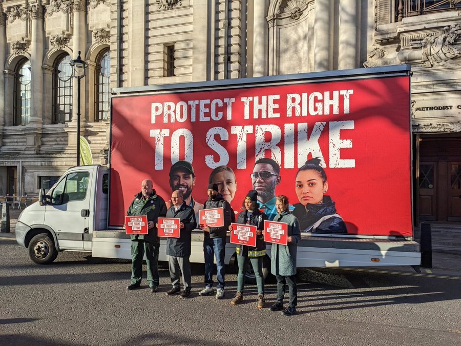 Five workers, including a firefighter, stand in front of a mobile billboard. The mobile billboard reads: protect the right to strike. The image is from the TUC day of action on February 1st 2023