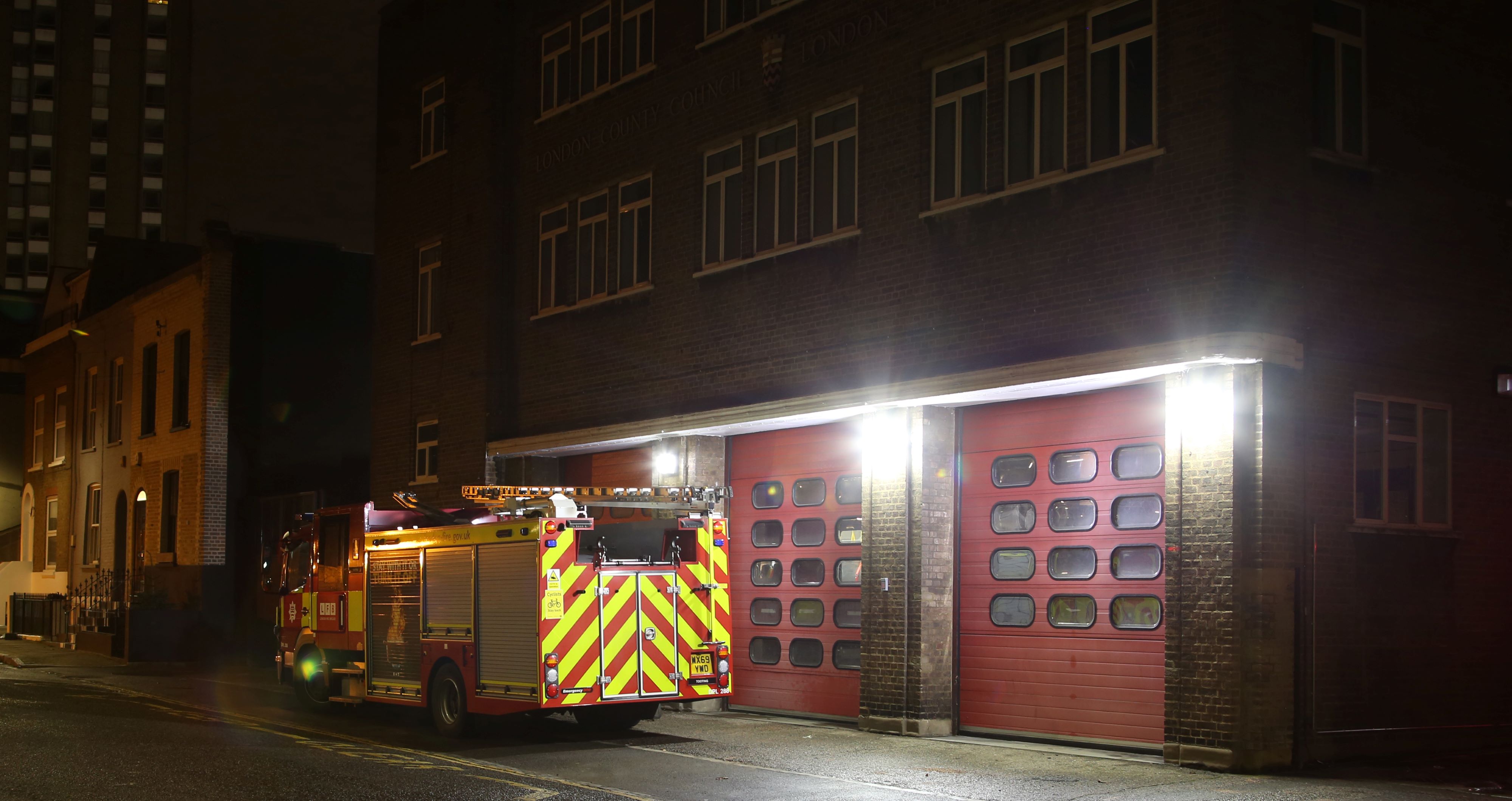 Fire station with fire appliance outside at night