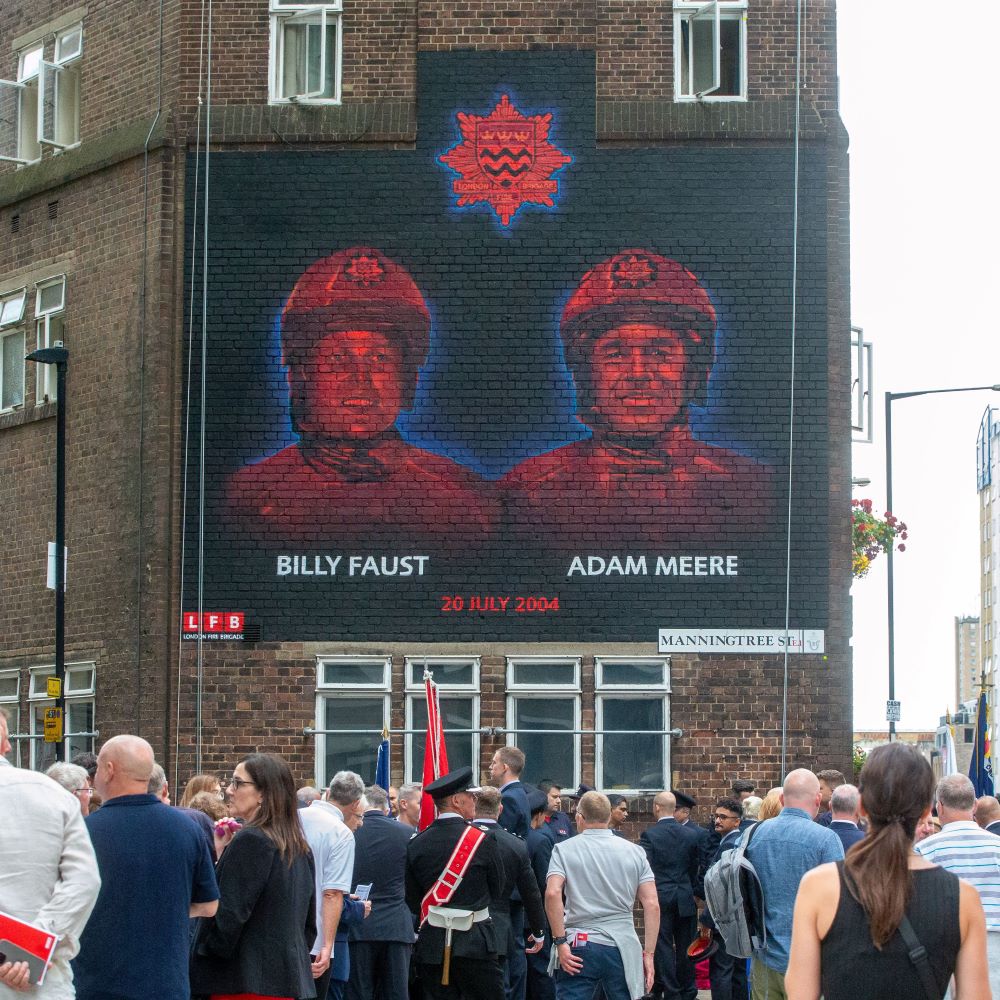 Mural painted on a brick wall in London depicting firefighters Adam Meere and Billy Faust