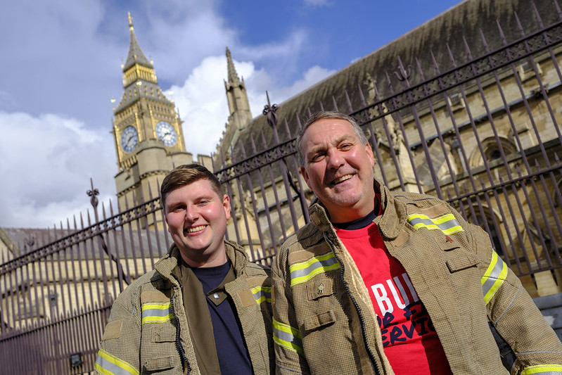 Two firefighters in tunics outside houses of parliament