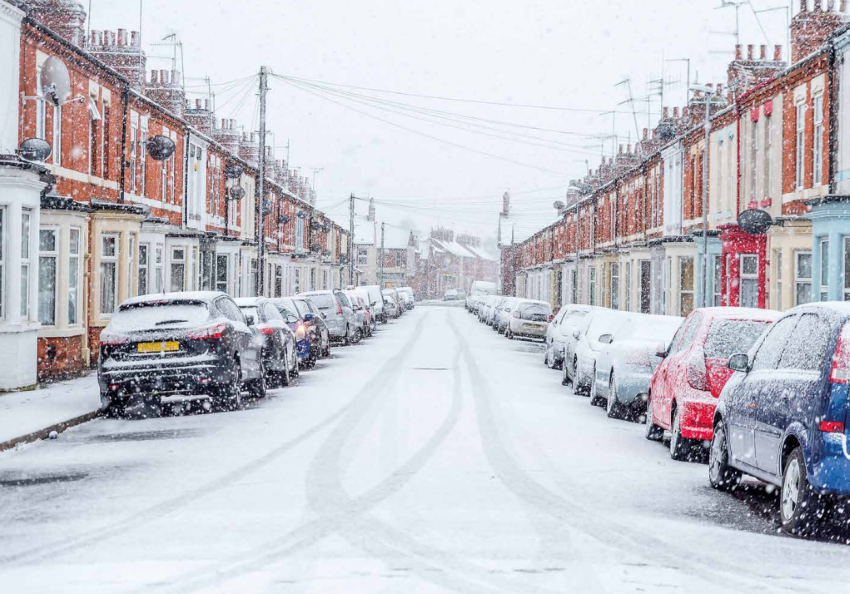 A snowy residential street with cars