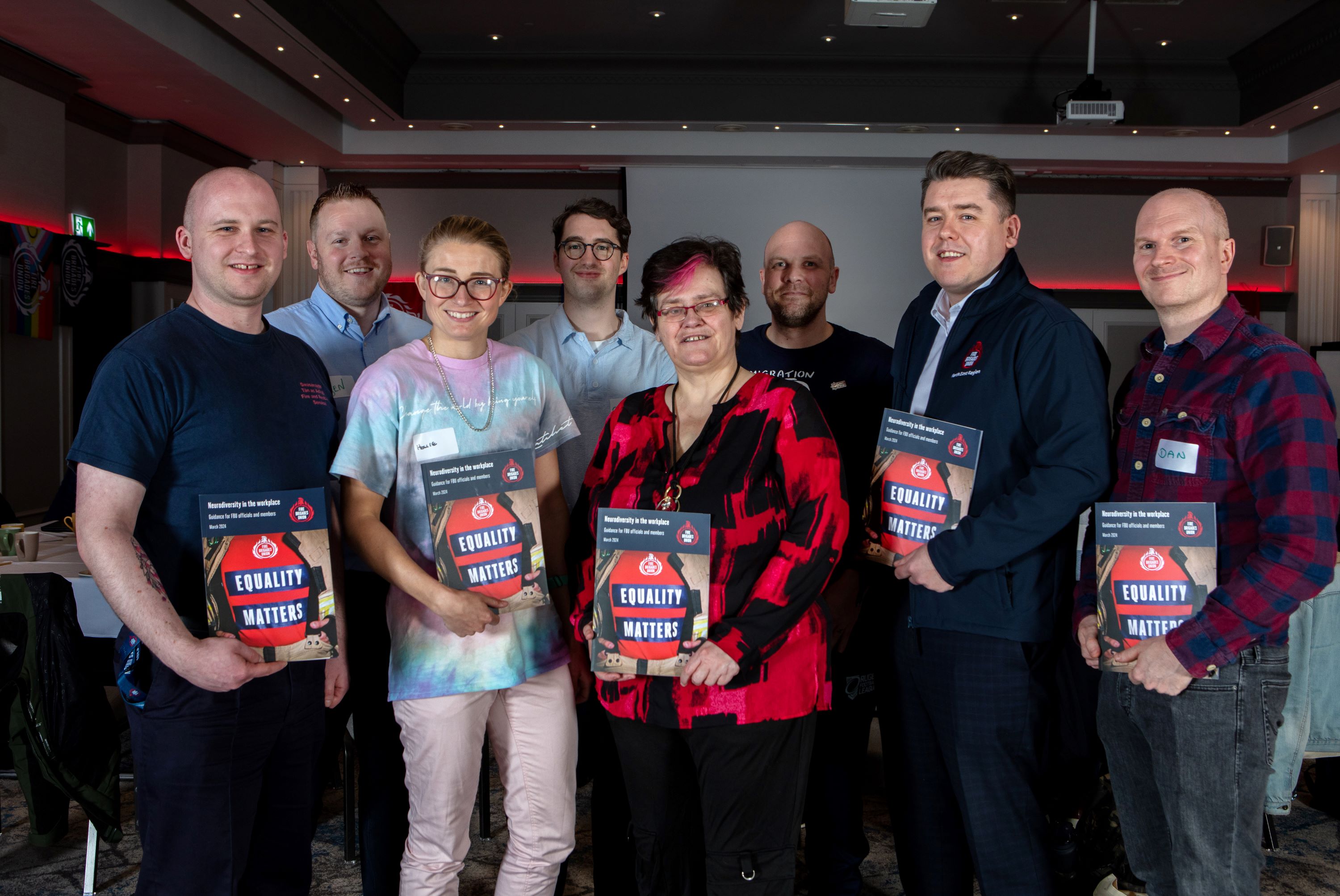 A group of FBU members hold up the FBU neurodiversity in the workplace guidance