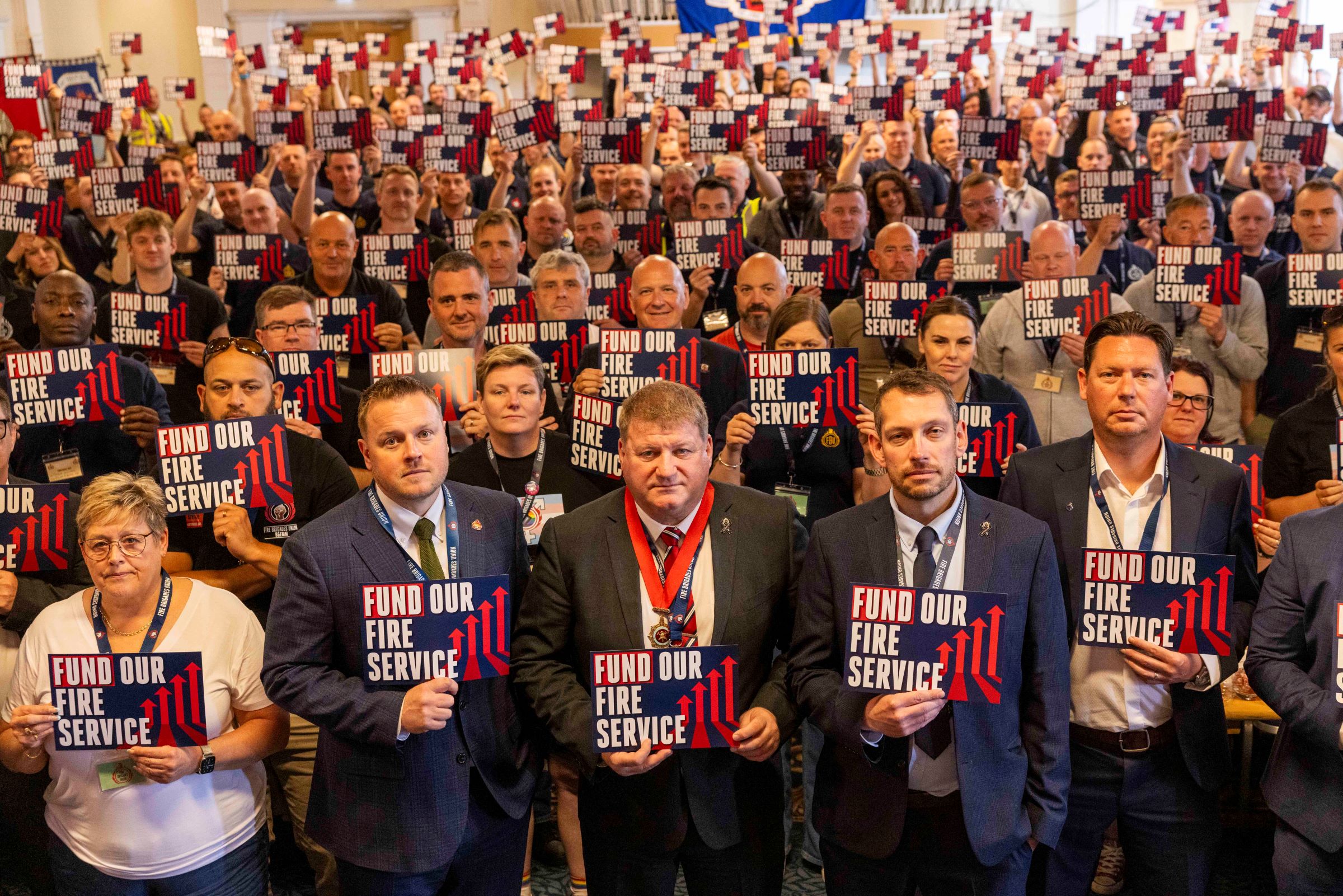 FBU conference 2025 delegates holding signs saying fund our fire service