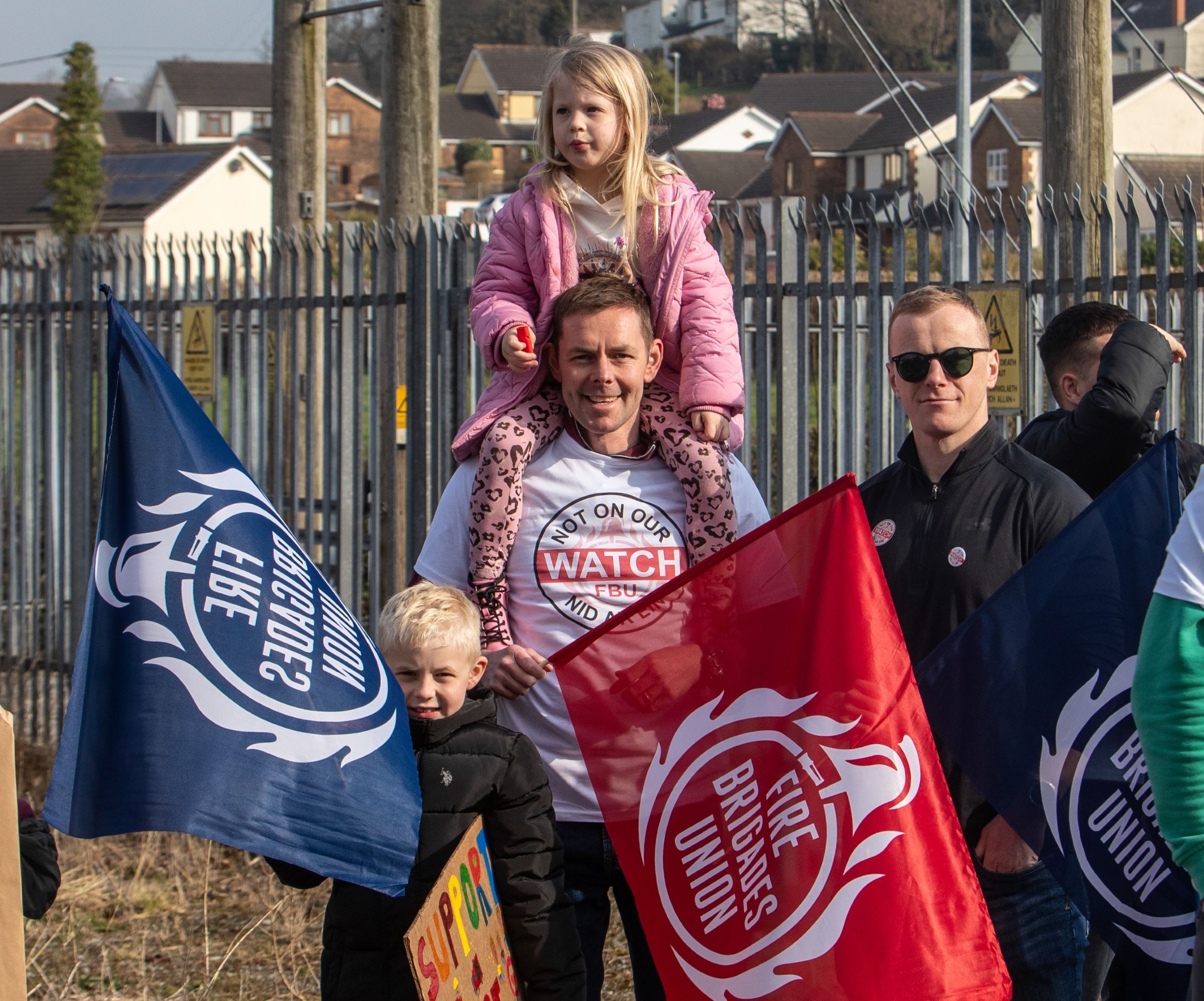 FBU member holding FBU flag with a child on his shoulders