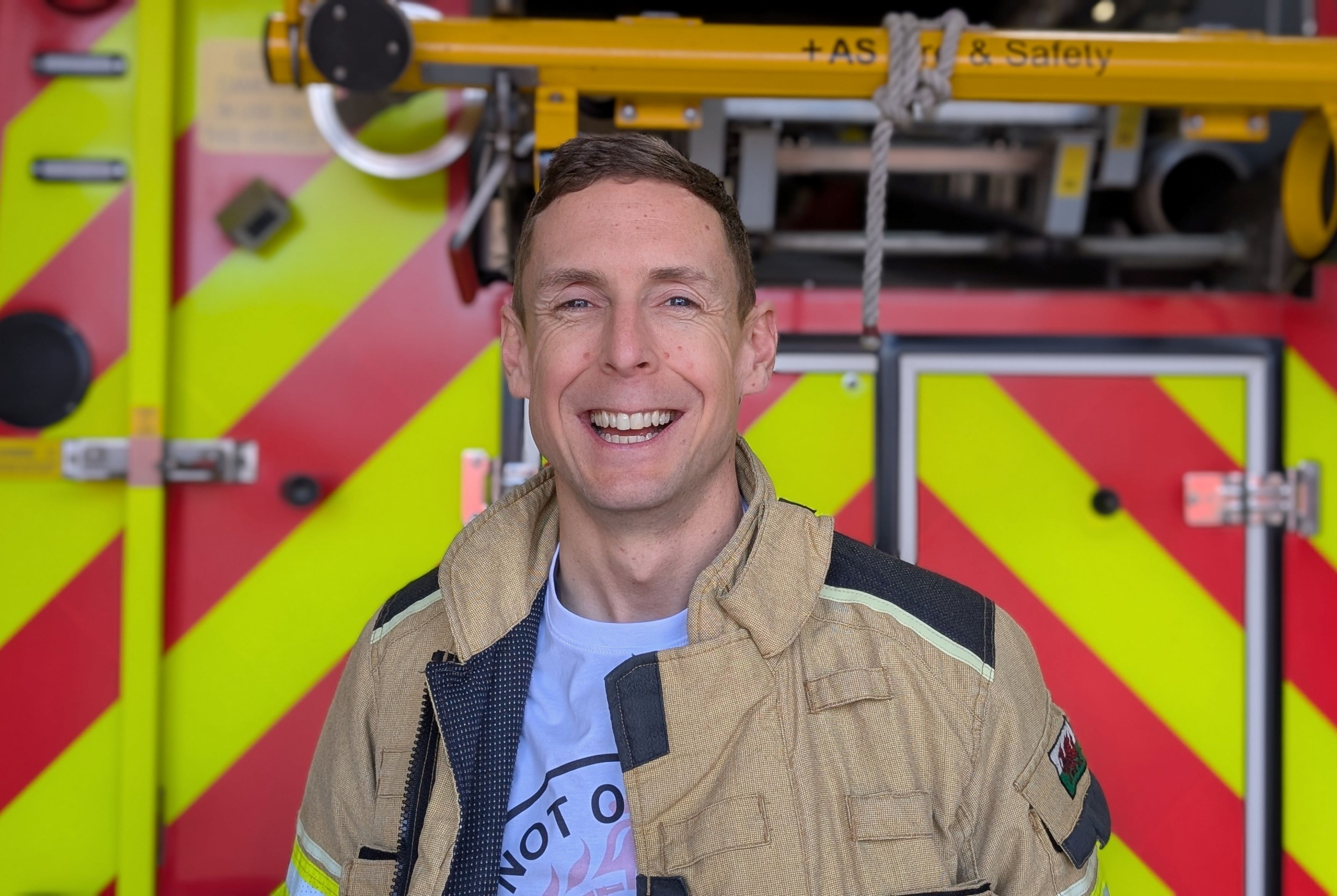 Tom Wass smiles at camera in front of a fire engine