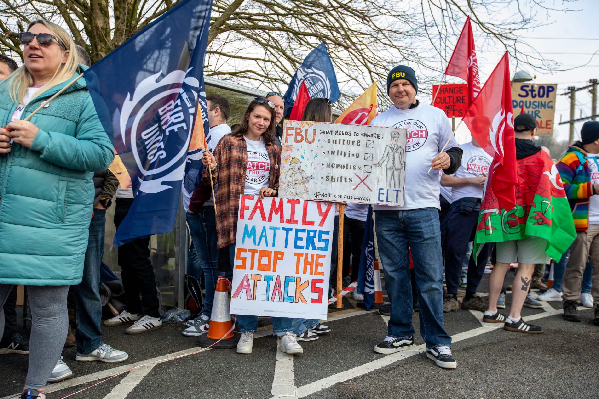 Firefighters gathered at a rally holding a sign reading 'family matters stop the attacks'