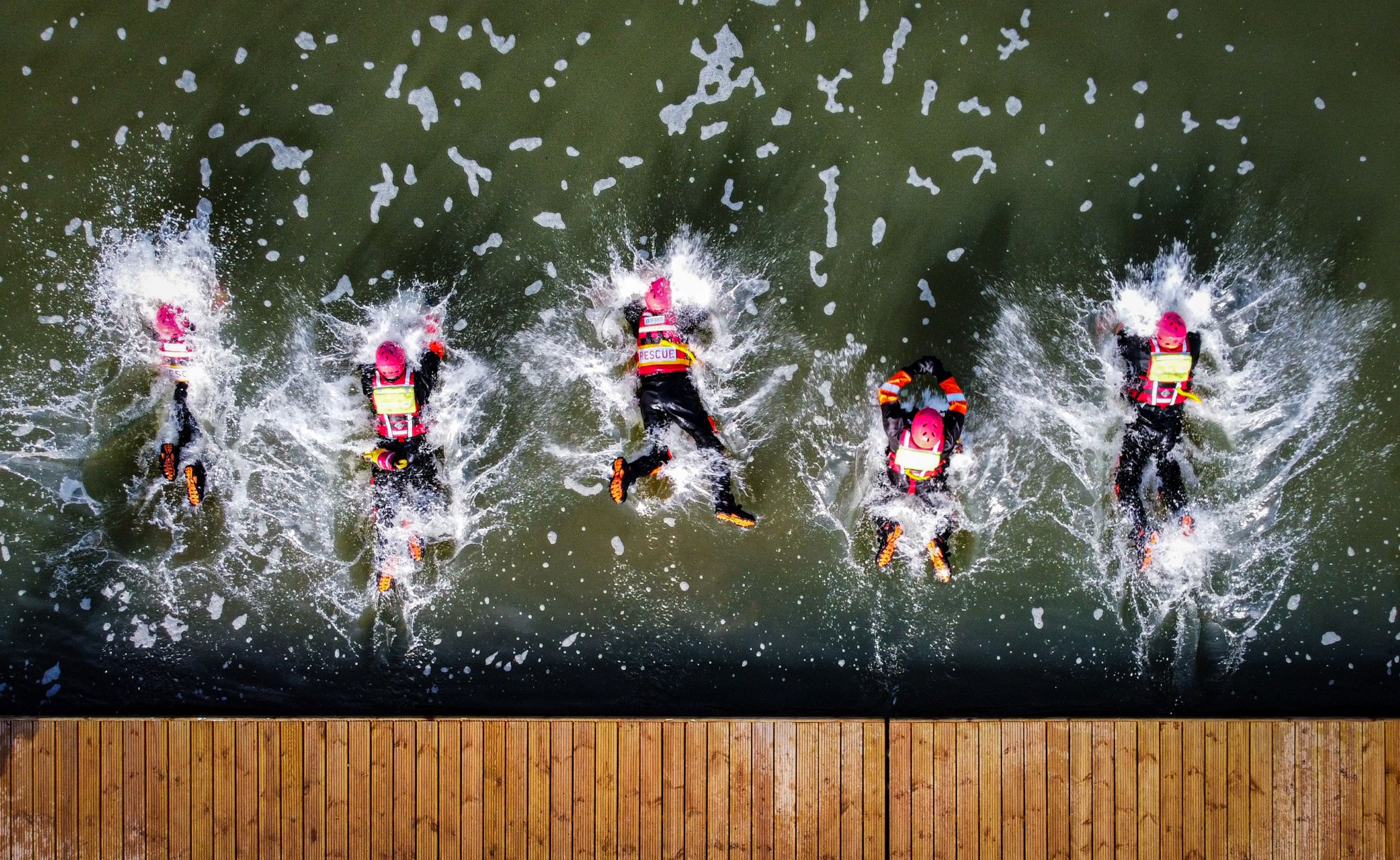Firefighters jump into water from an aerial view