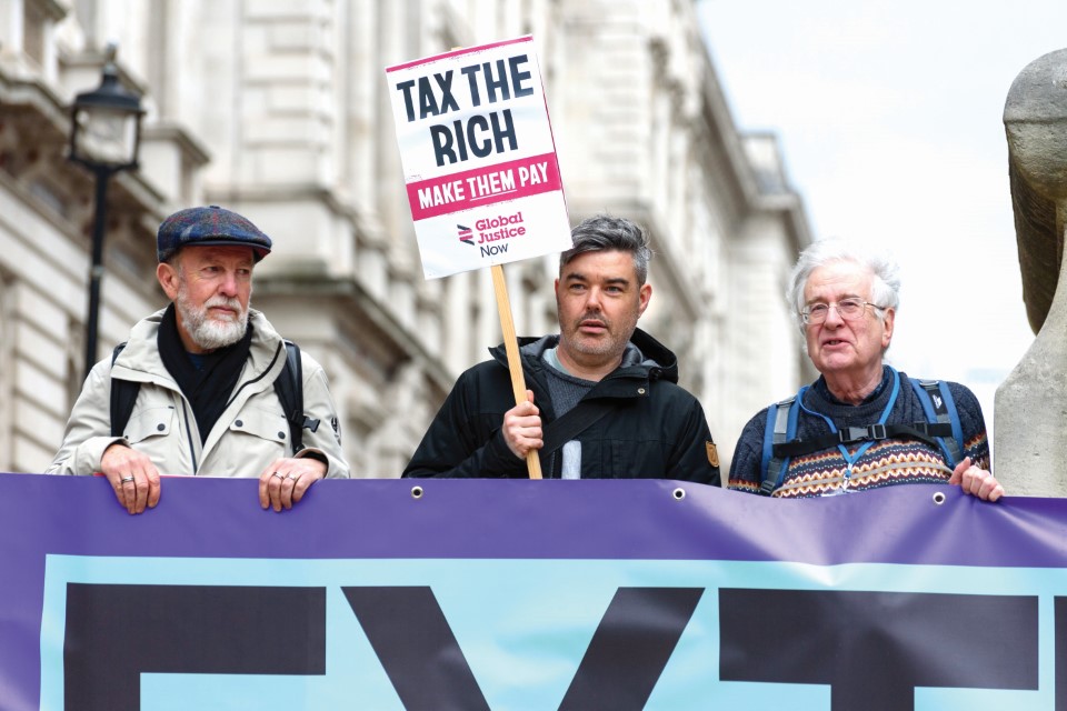 James O'Nions holding a placard reading "tax the rich"