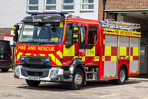 a hampshire and isle of wight fire engine sitting in front of a station, stationary