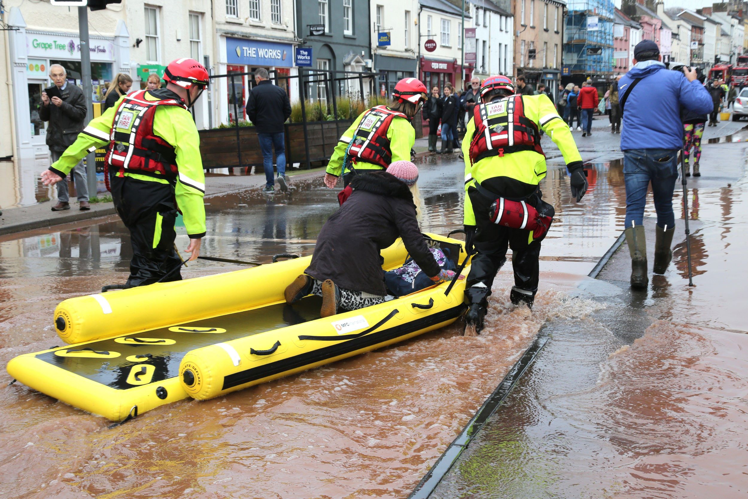 Firefighters towing a rescue boat in flood water
