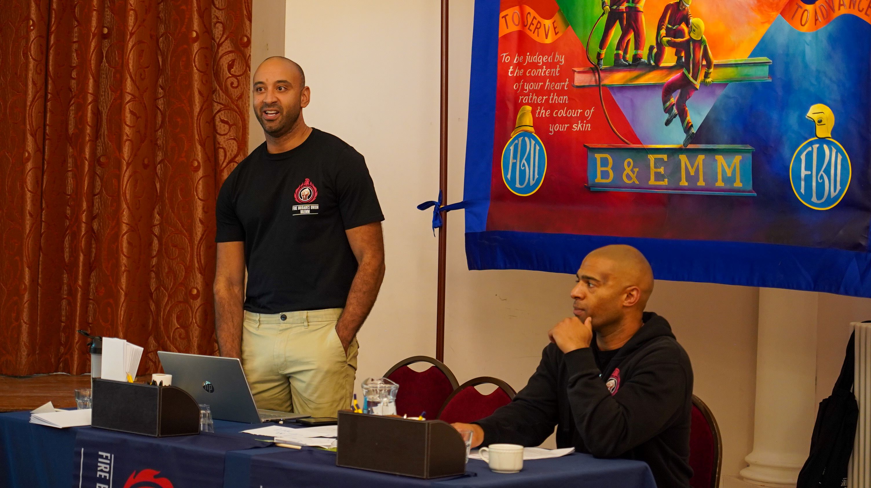 Adam McKenzie standing in front of an FBU banner at an event