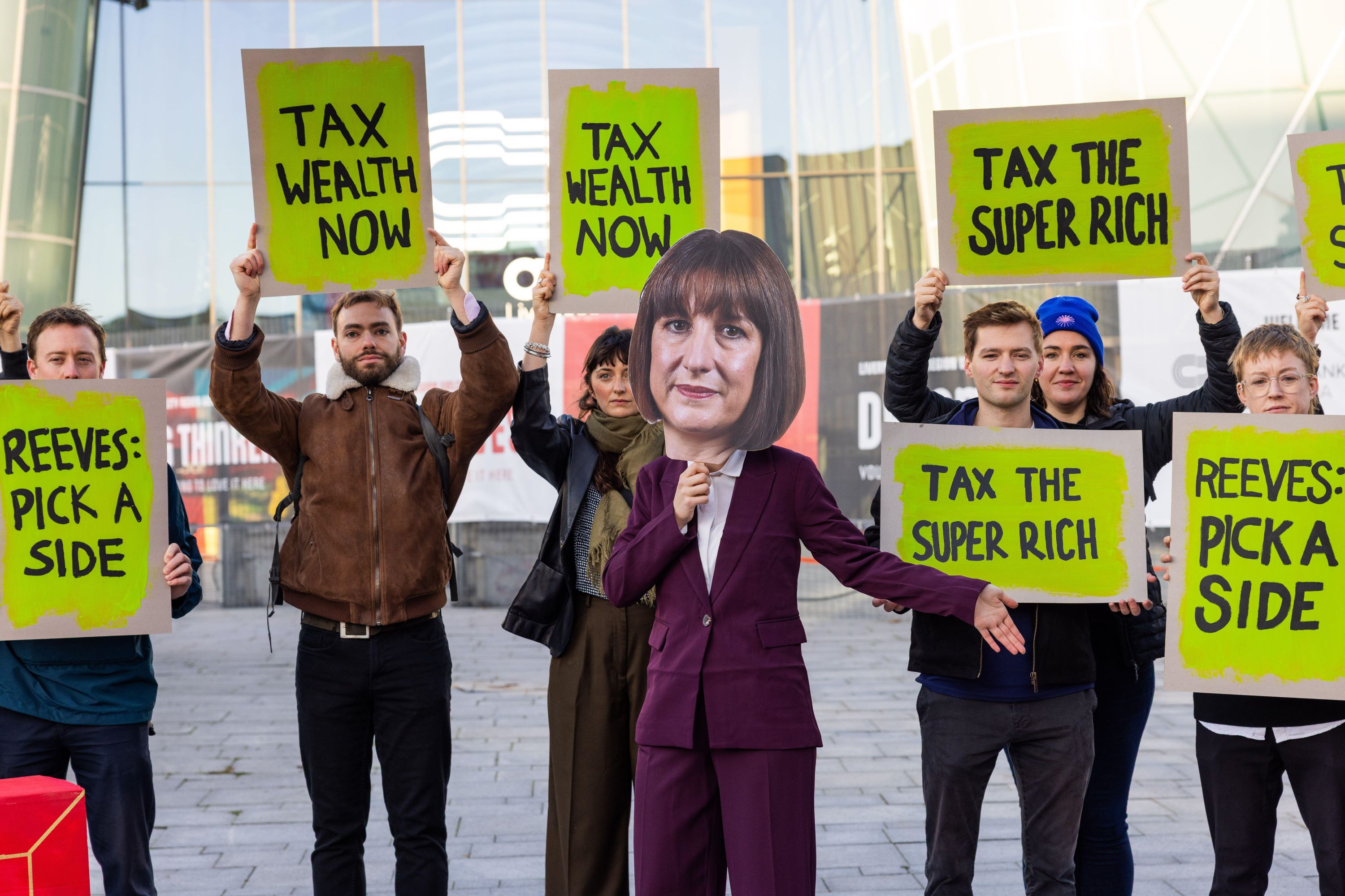 Protestors hold 'tax the rich signs', with one dressed as Rachel Reeves