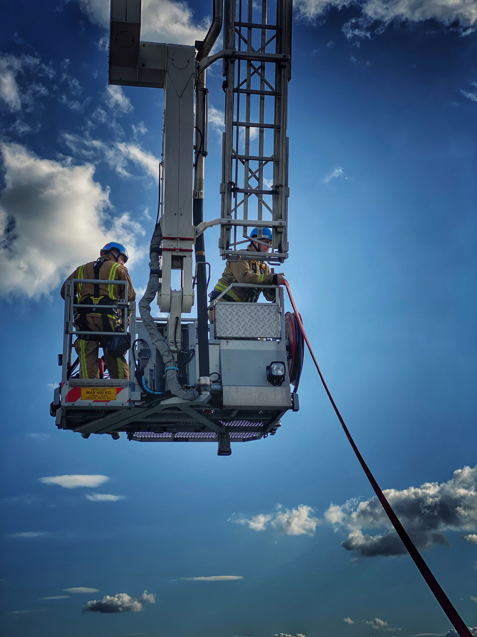 Firefighters on an aerial ladder platform against blue sky backdrop