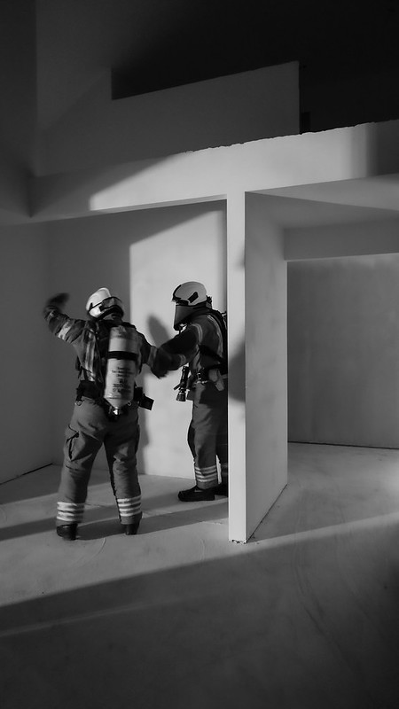 Two firefighters in breathing apparatus, in black and white
