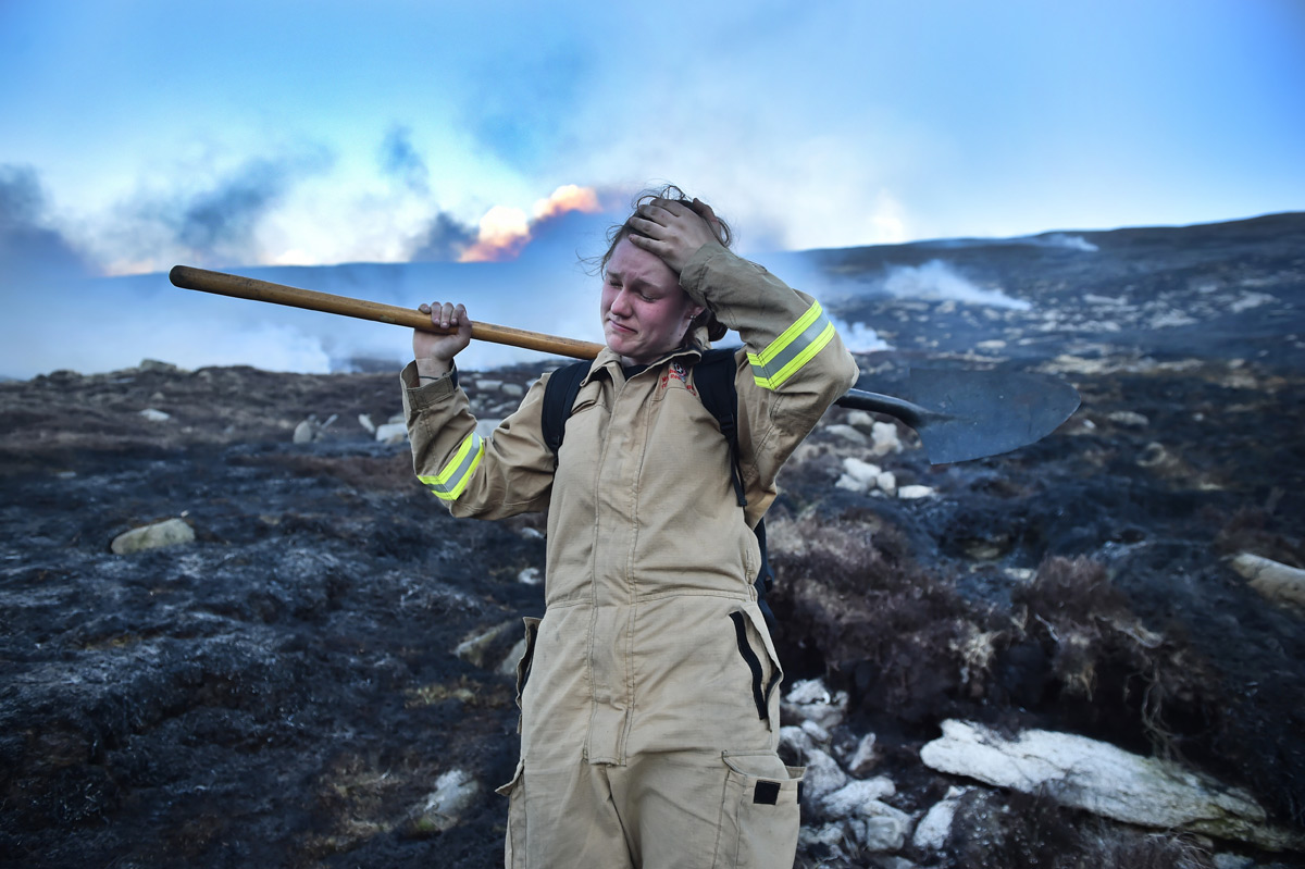 A firefighter wipes sweat from her brow