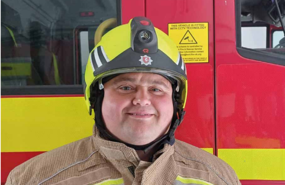 Dave Turner smiles at camera wearing firefighter helmet 