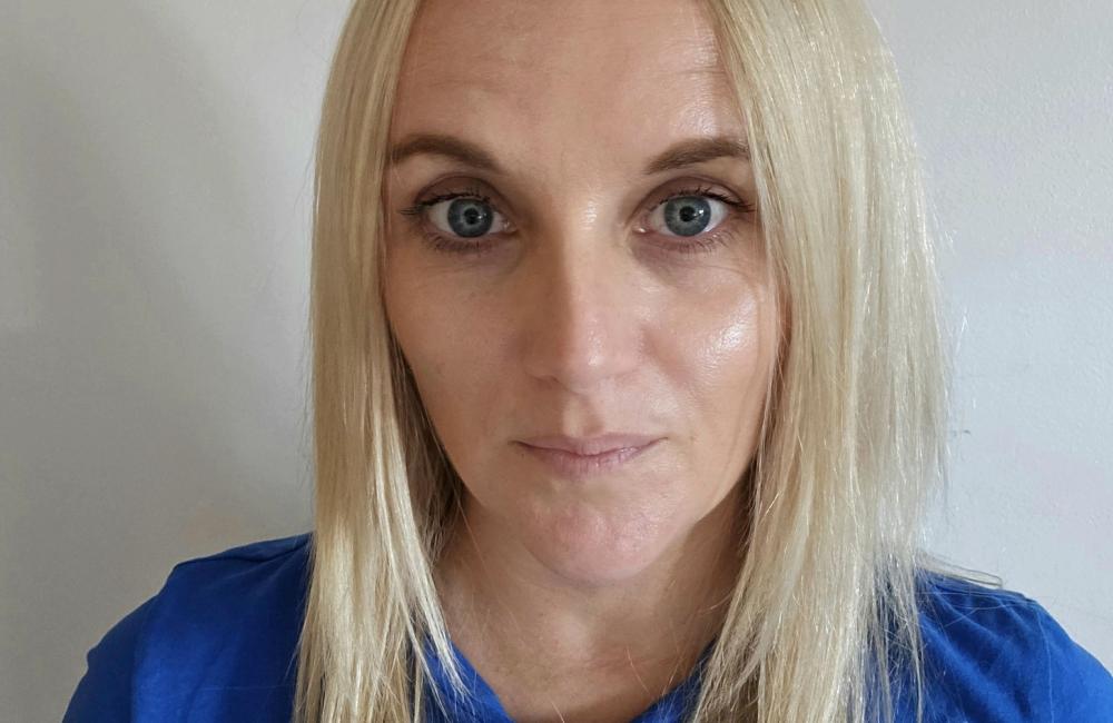 Woman with blond hair looks into camera