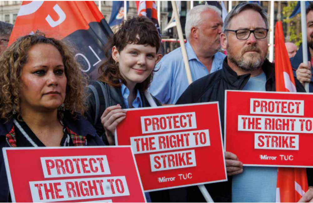Three demonstrators hold protect the right to strike placards at TUC rally