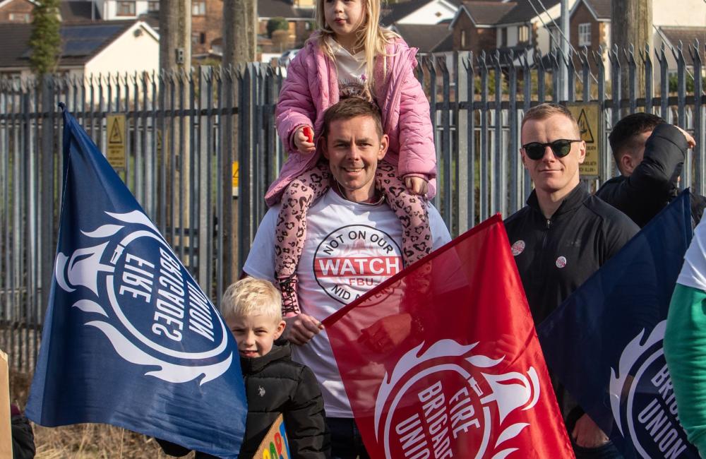FBU member holding FBU flag with a child on his shoulders