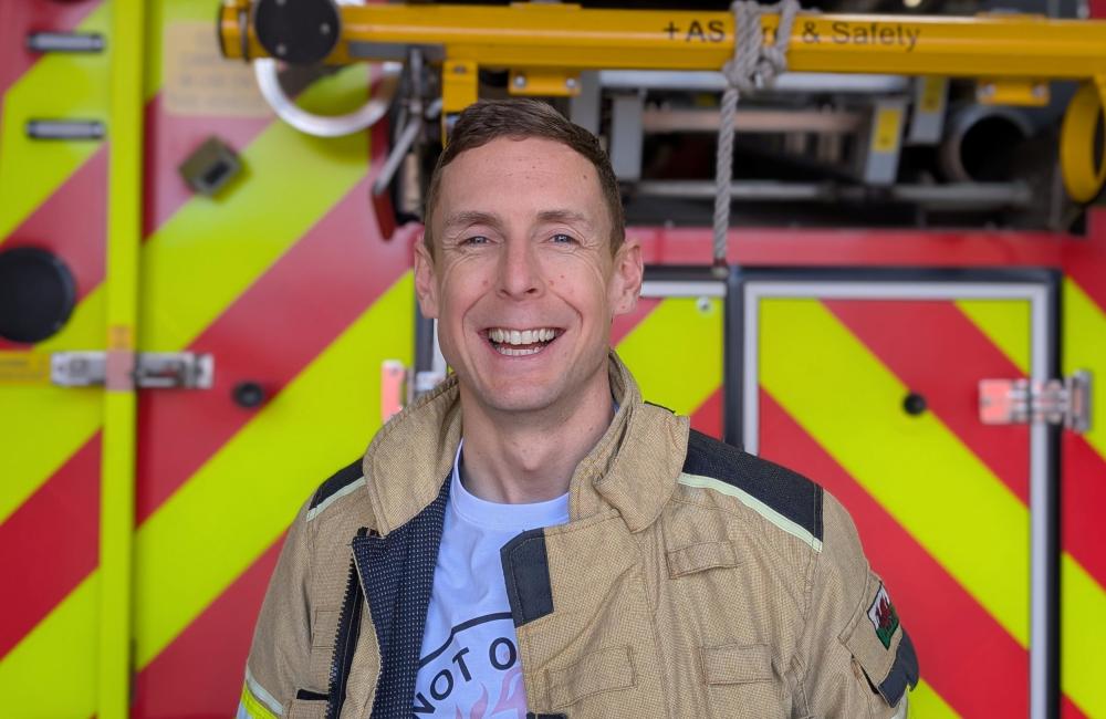 Tom Wass smiles at camera in front of a fire engine