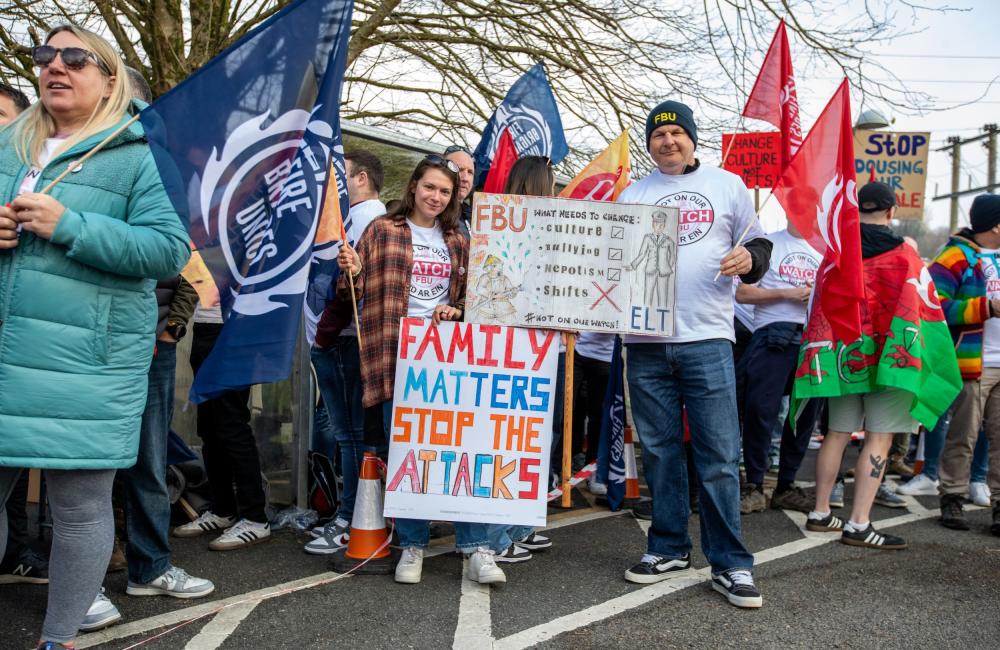 Firefighters gathered at a rally holding a sign reading 'family matters stop the attacks'