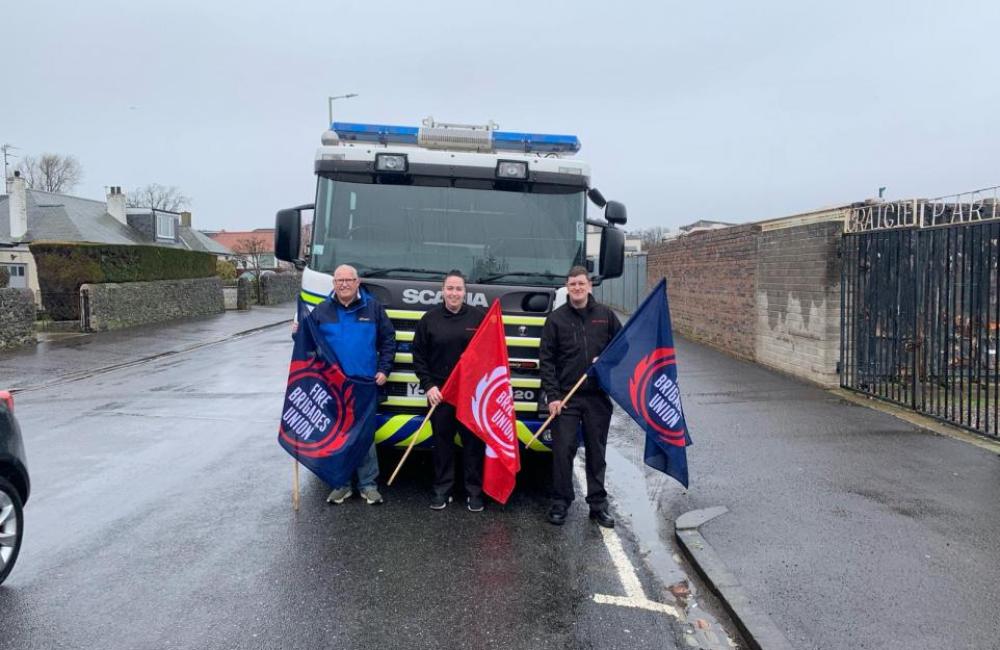 Three FBU members with flags stand in front of the donated fire engine