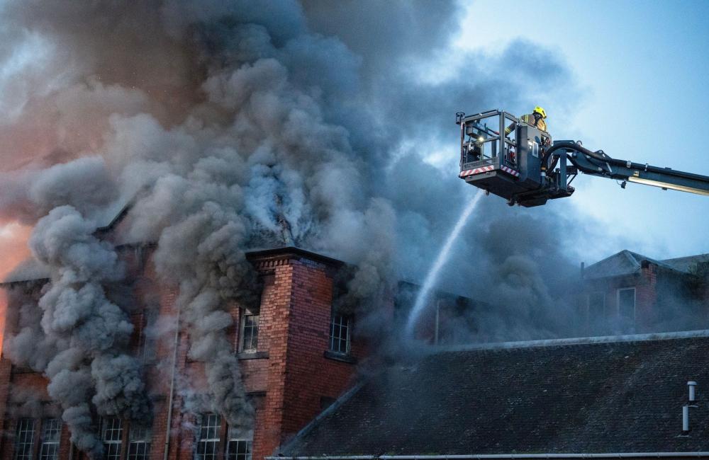 Firefighters on an aerial ladder platform over a burning roof