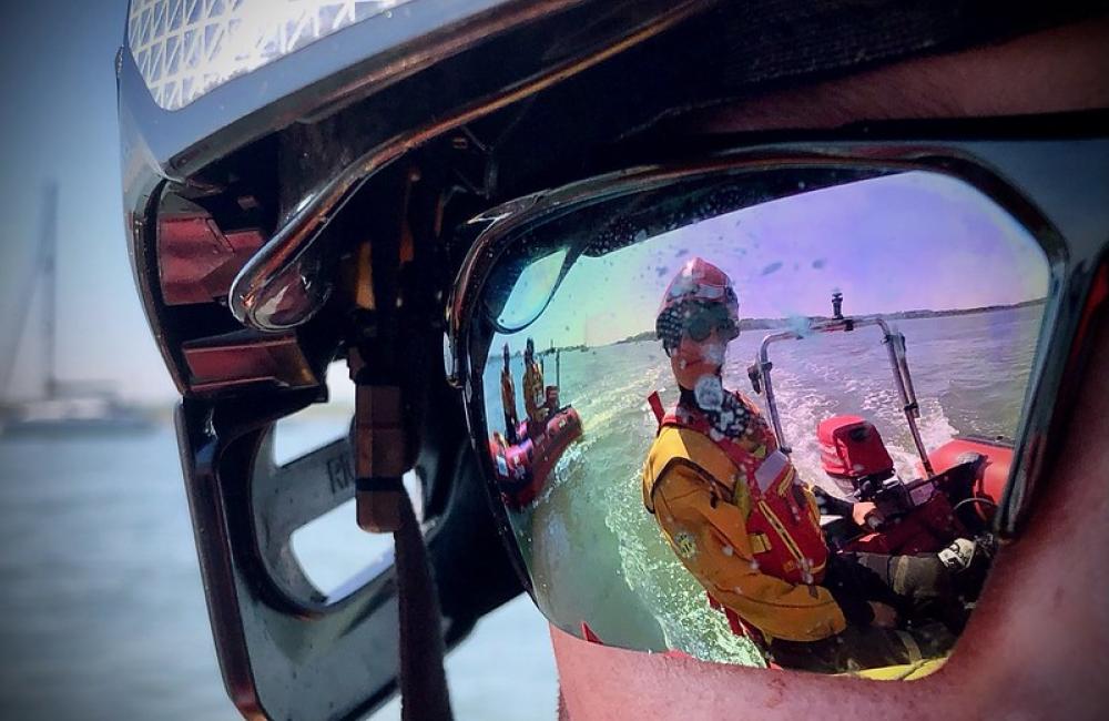Firefighter wearing water goggles with rescue boat refected