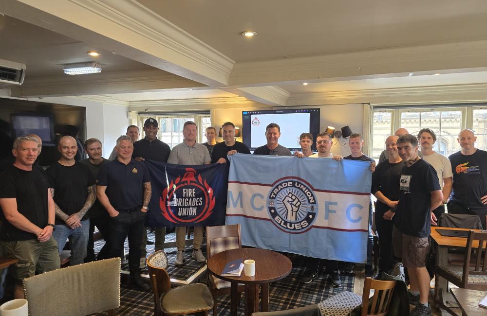 Members with a Trades Union Blues banner at an FBU meeting