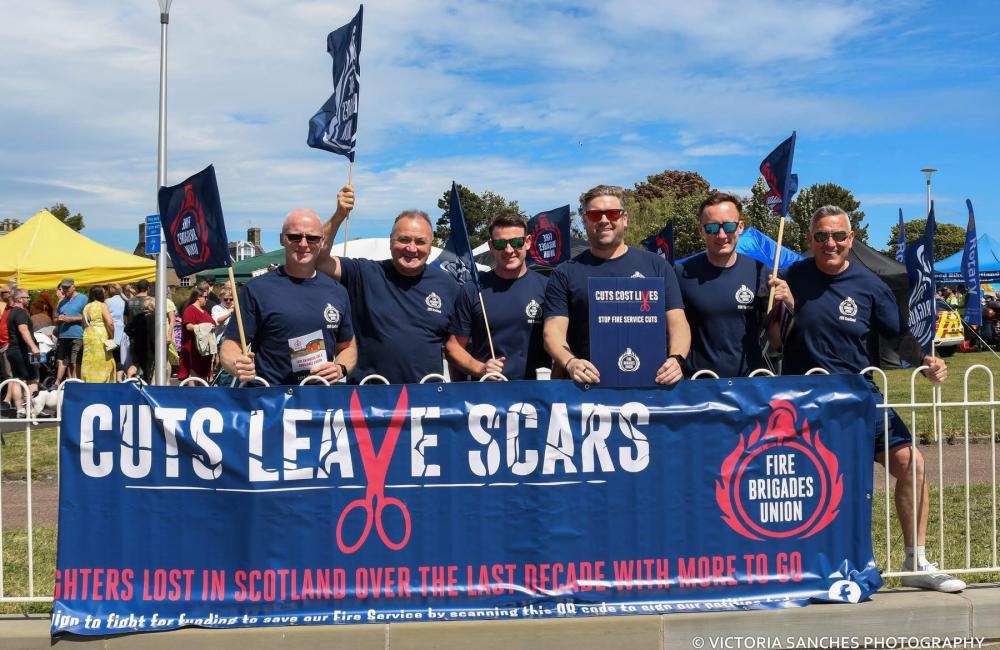 FBU members holding large banner reading 'cuts leave scars' with FBU logo