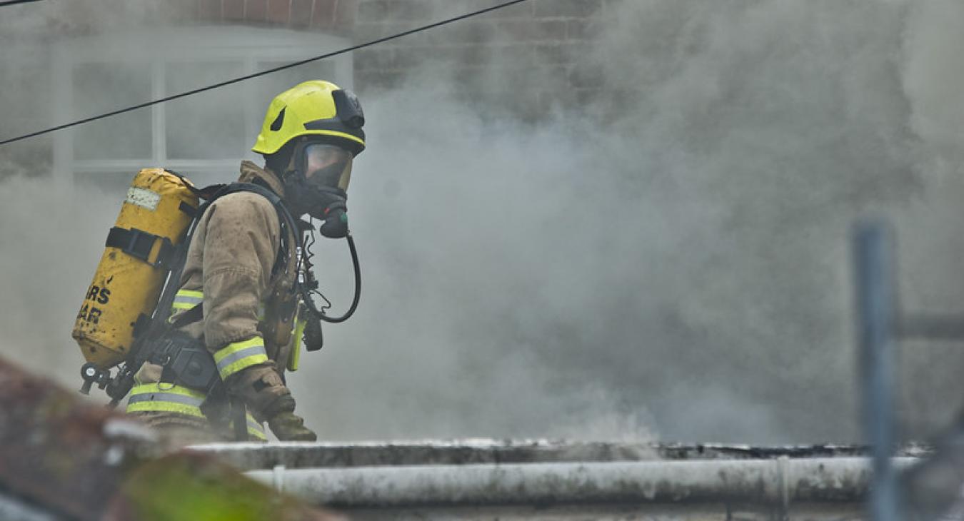 A firefighter wearing breathing apparatus amongst smoke 
