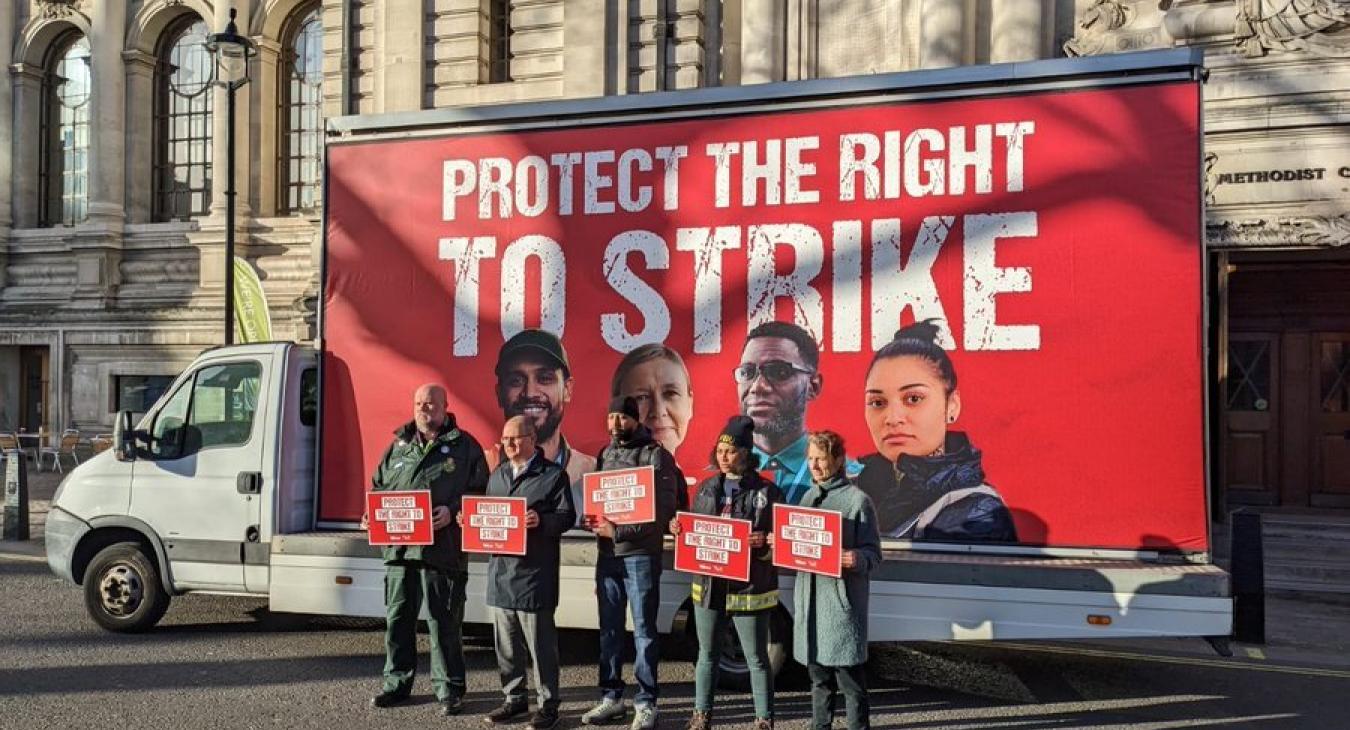 Five workers, including a firefighter, stand in front of a mobile billboard. The mobile billboard reads: protect the right to strike. The image is from the TUC day of action on February 1st 2023
