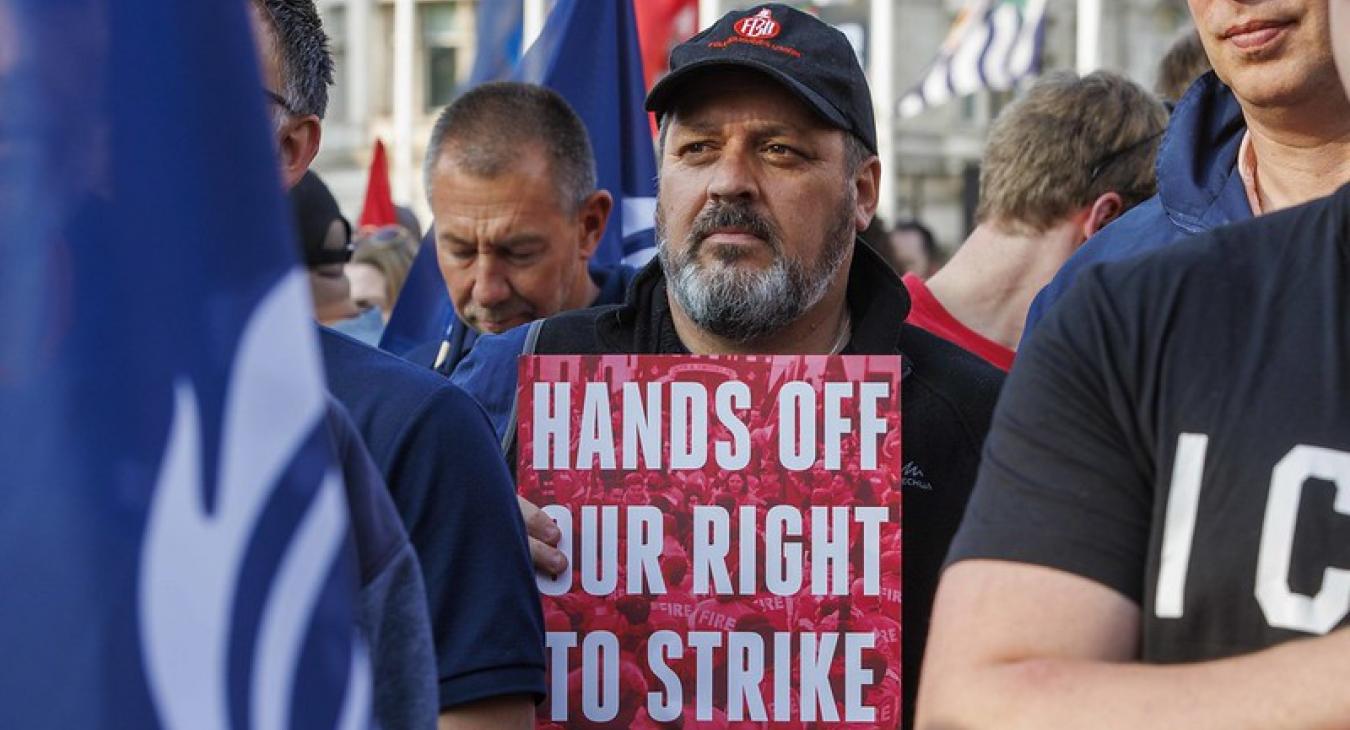 Firefighter with 'hands off our right to strike' placard