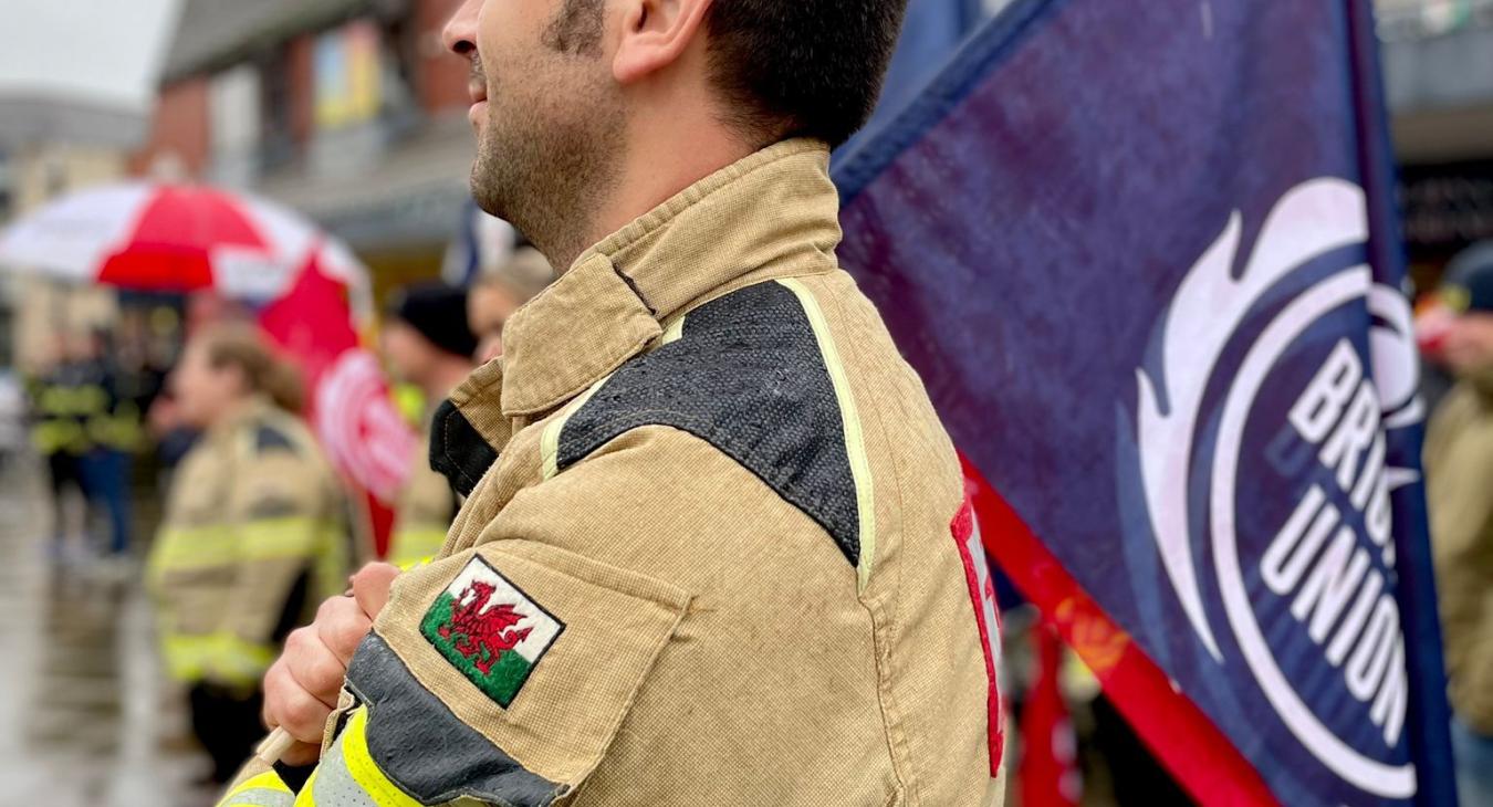 Firefighter with FBU flag and Welsh crest on fire tunic