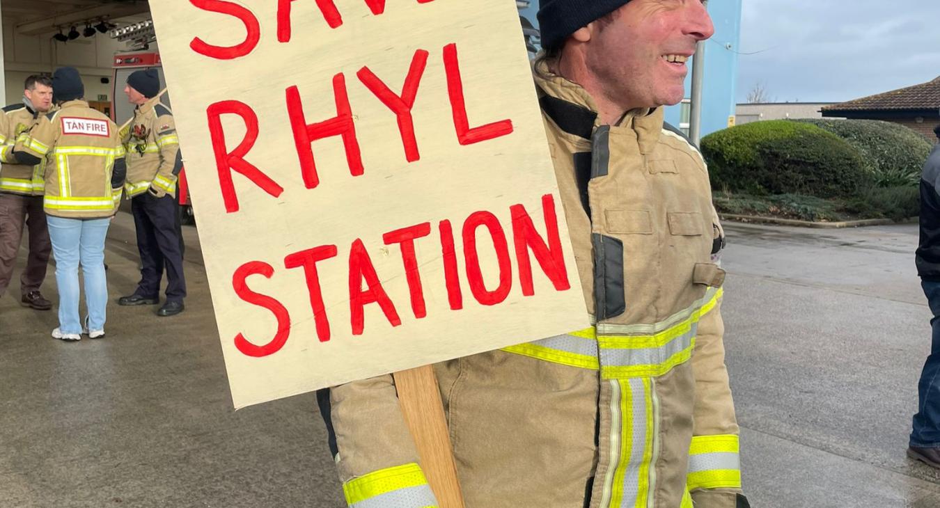 Firefighter holds save rhyl station sign