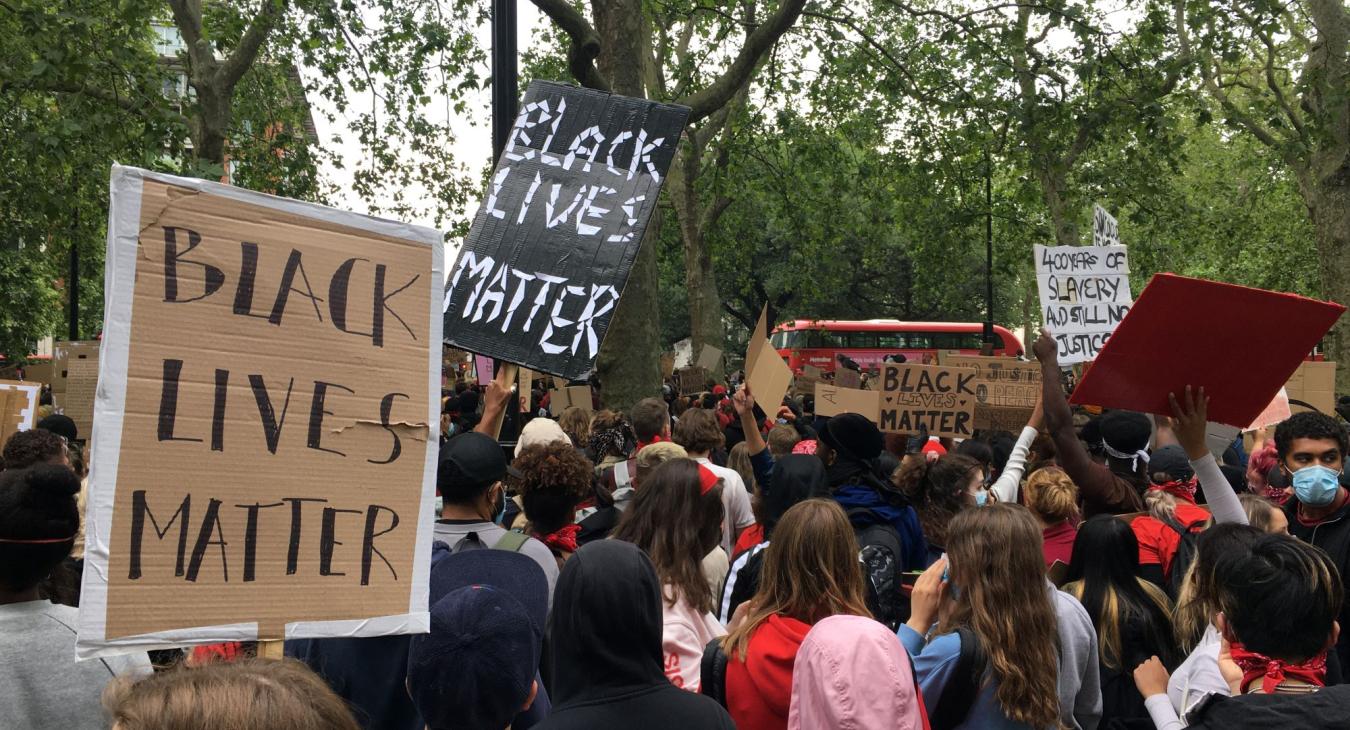 Protestors hold signs that read "Black Lives Matter"