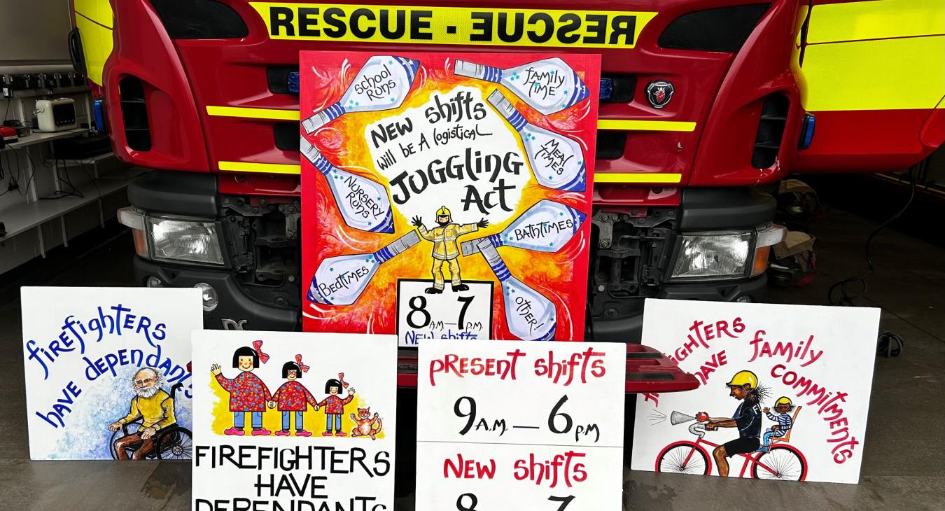 Placards depicting firefighters with children and elderly relatives oppose changes to shifts