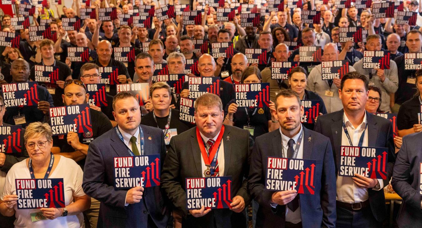 FBU conference 2025 delegates holding signs saying fund our fire service