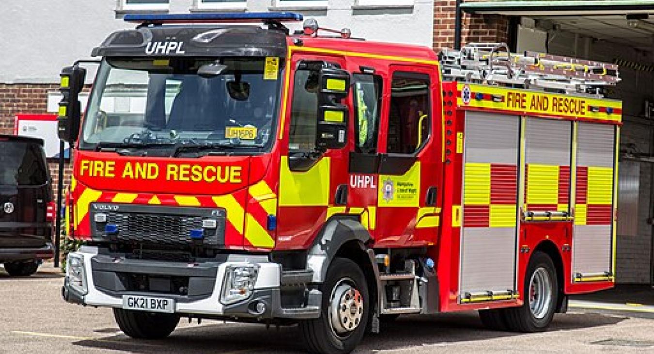 a hampshire and isle of wight fire engine sitting in front of a station, stationary