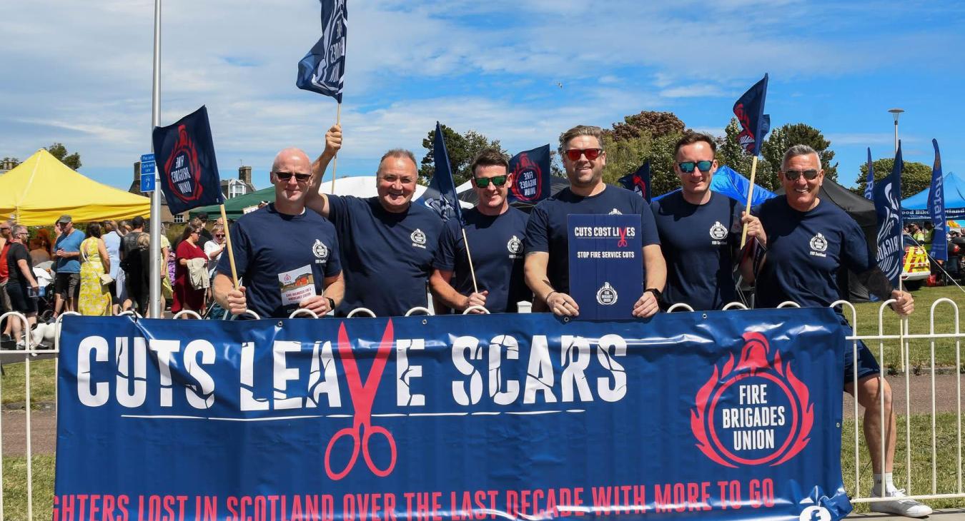 FBU members holding large banner reading 'cuts leave scars' with FBU logo