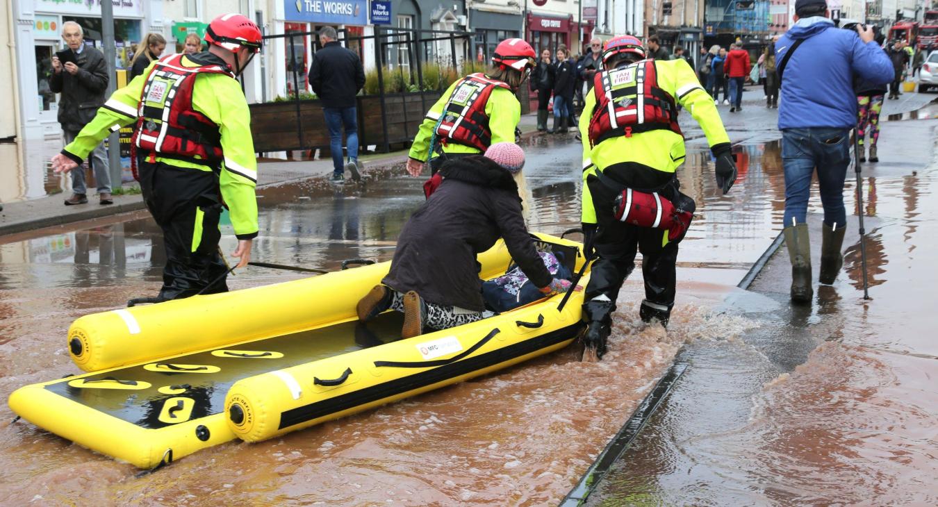 Firefighters towing a rescue boat in flood water