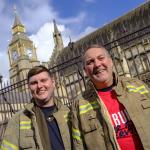 Two firefighters in tunics outside houses of parliament