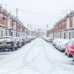 A snowy residential street with cars