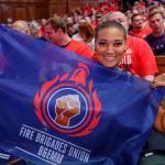 Kasey LeGall at a rally holding a BEMM section flag