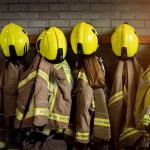 Fire kits handing up in a row with helmets on pegs