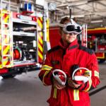 A firefighter in kit at fire station wearing a VR headset