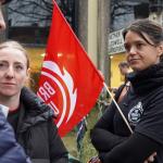 A woman holding an FBU flag while talking to fellow union members
